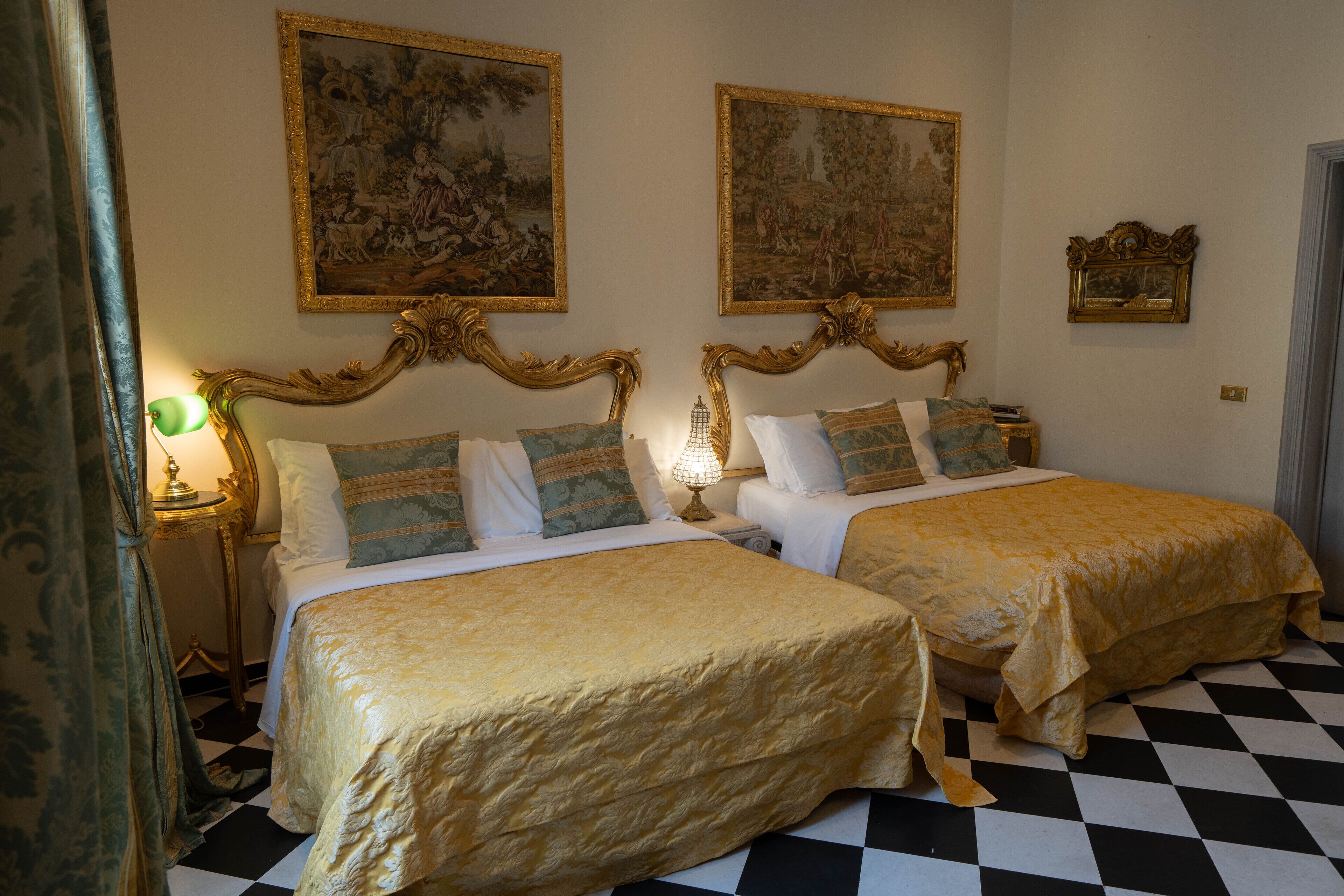 A hotel room with two beds, a checkered floor, and ornate wall decorations.