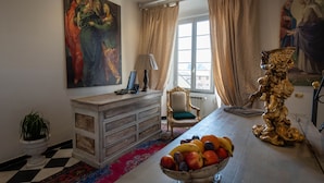 A room with a dining table, a fruit bowl, a lamp, a chair, and a painting on the wall. - San Giorgio Rooms (Genoa)