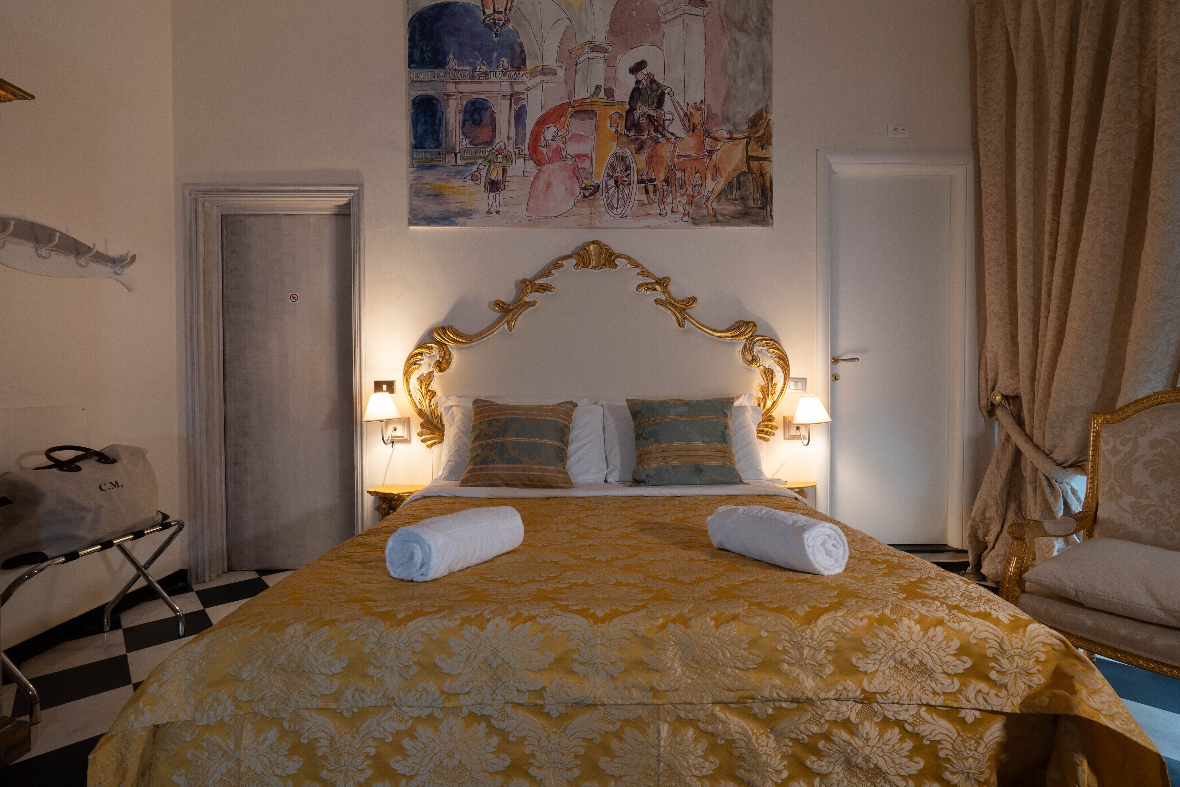 Quarto de hotel com uma cama grande, um quadro na parede e chão xadrez.