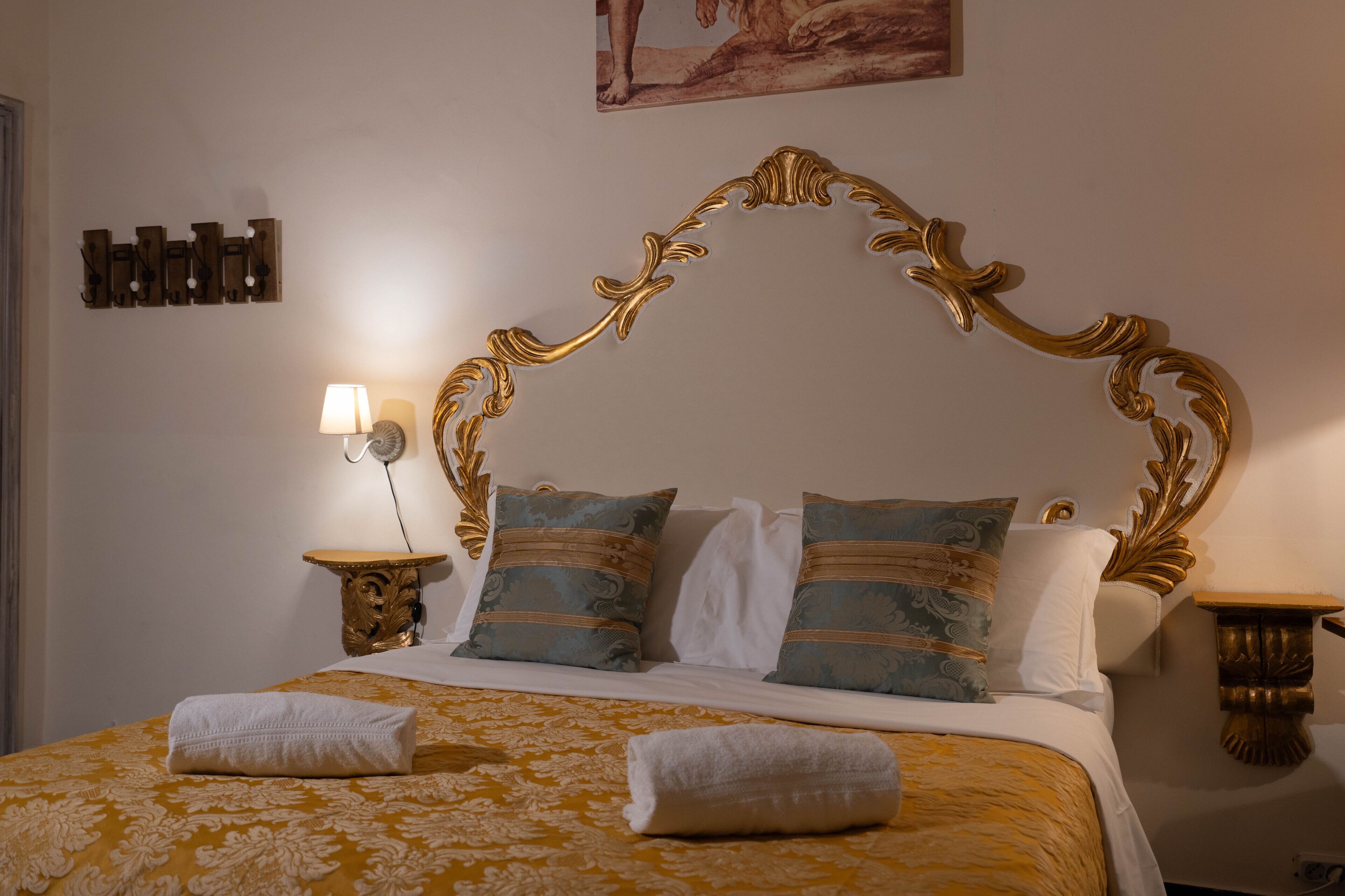 Ein Bett mit goldenem Kopfteil, Kissen mit blau-weißem Muster und einer gelben Blumenbettdecke.