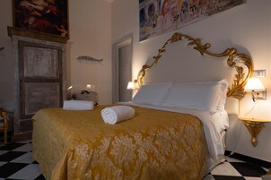 Een hotelkamer met een groot bed, twee bedlampen, een schilderij aan de muur en een zwart-wit geruite vloer.