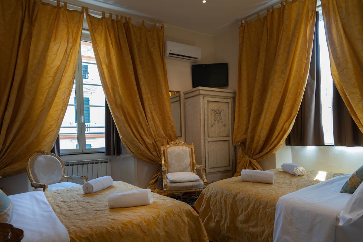 A hotel room with two beds, a chair, and a television.