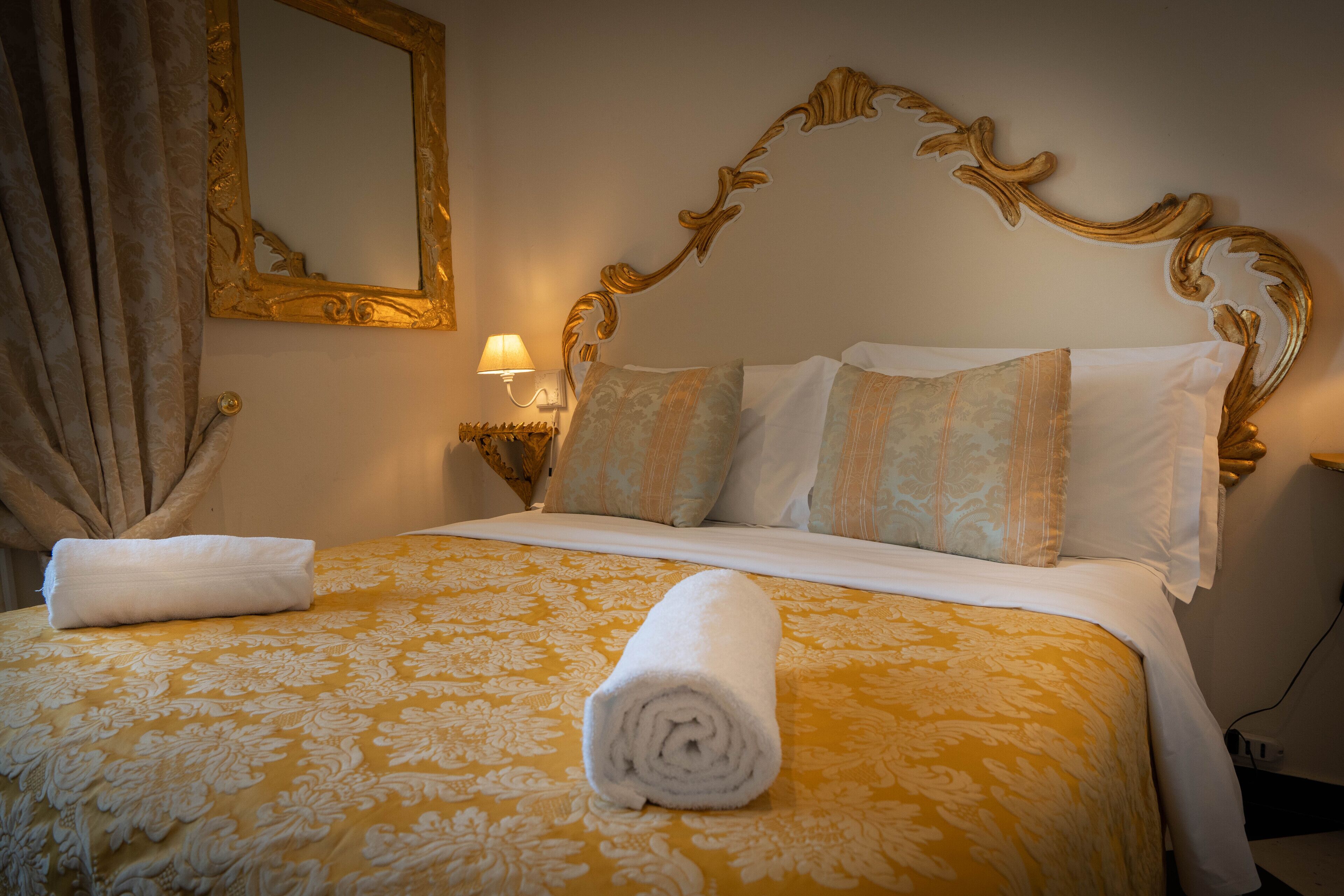 Una habitación de hotel con una cama grande, un cabecero ornamentado y un espejo en la pared.