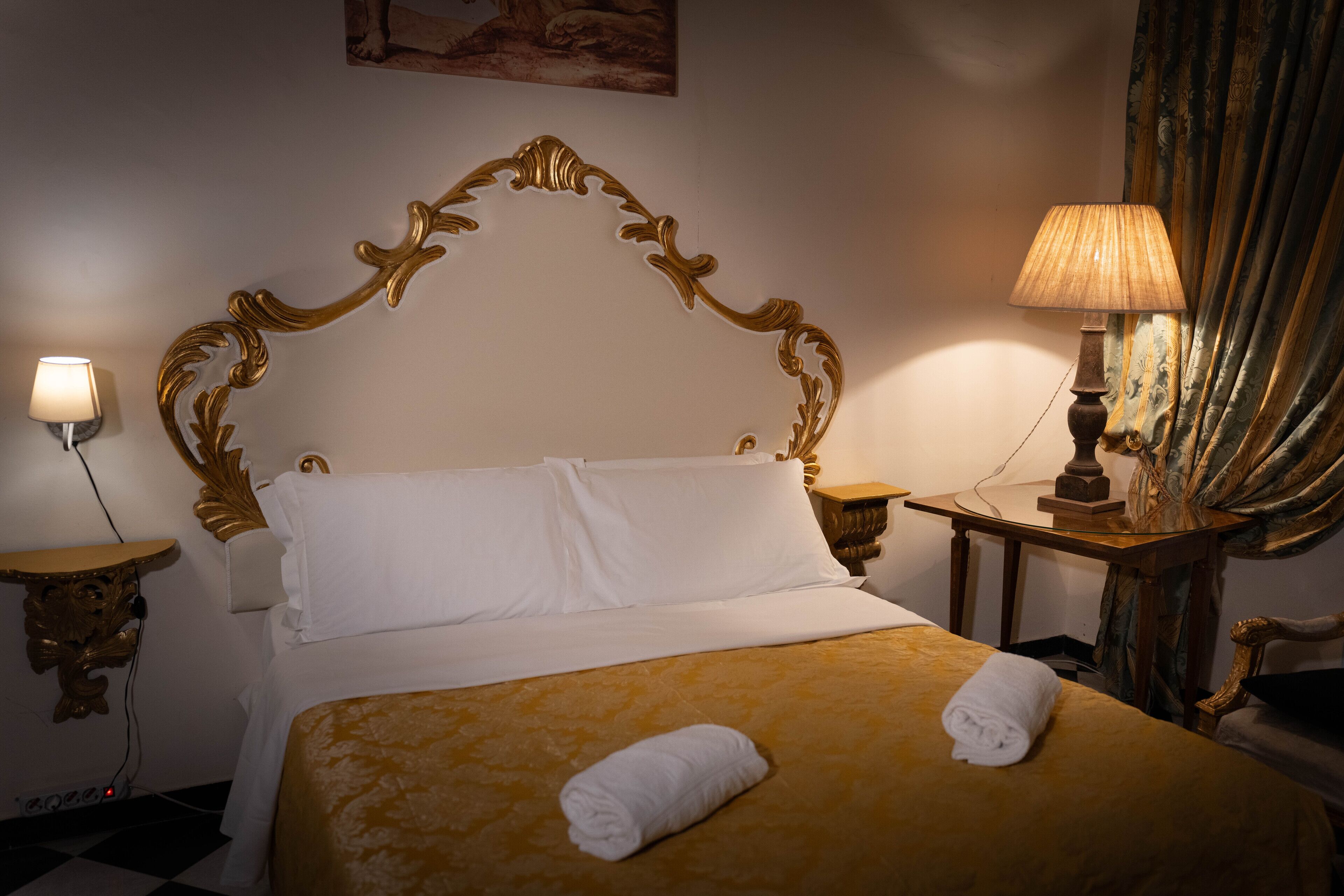 Una habitación de hotel con una cama grande, una mesita de noche con lámpara y un cuadro en la pared.