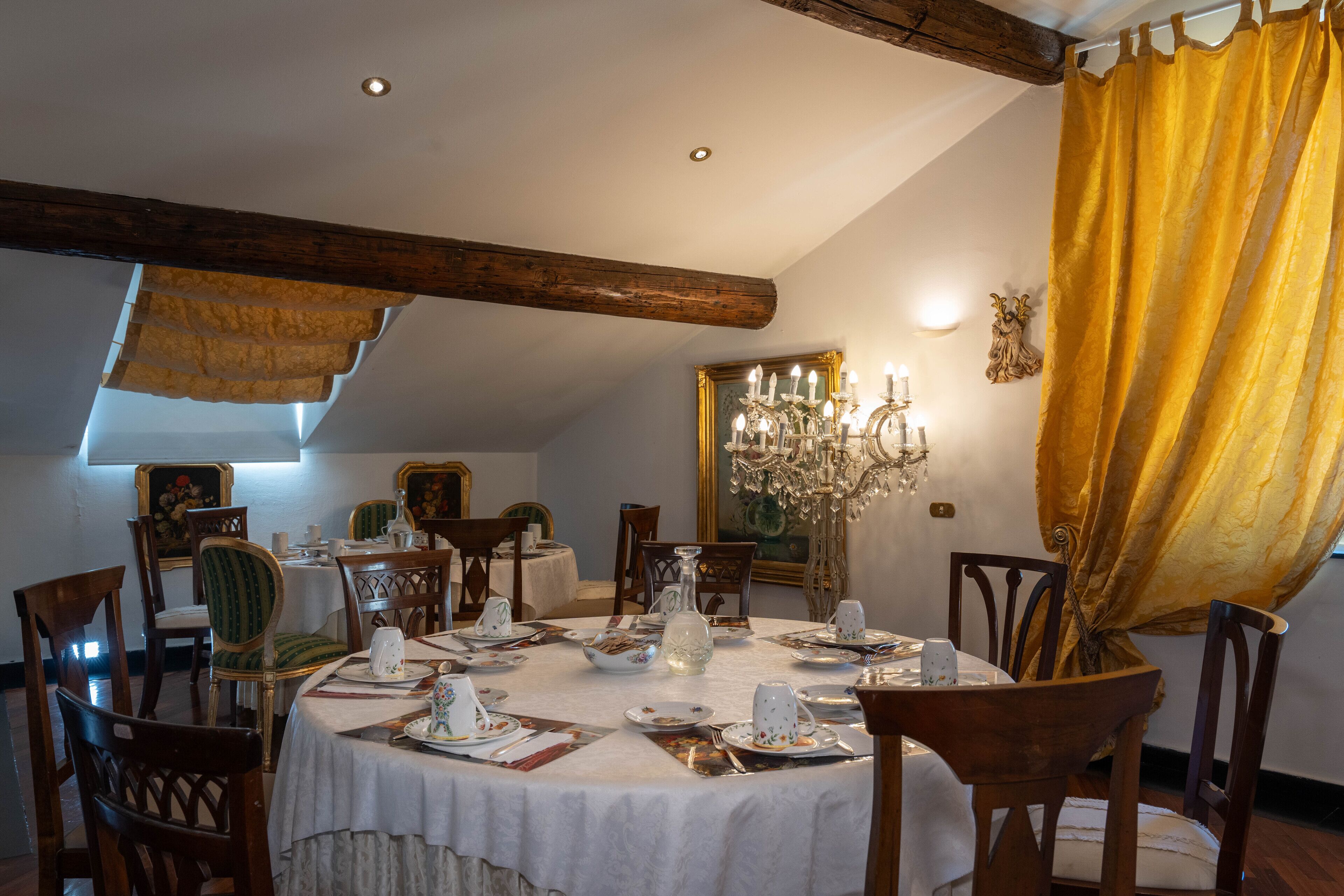 A dining area with a round table set for four, surrounded by wooden chairs.