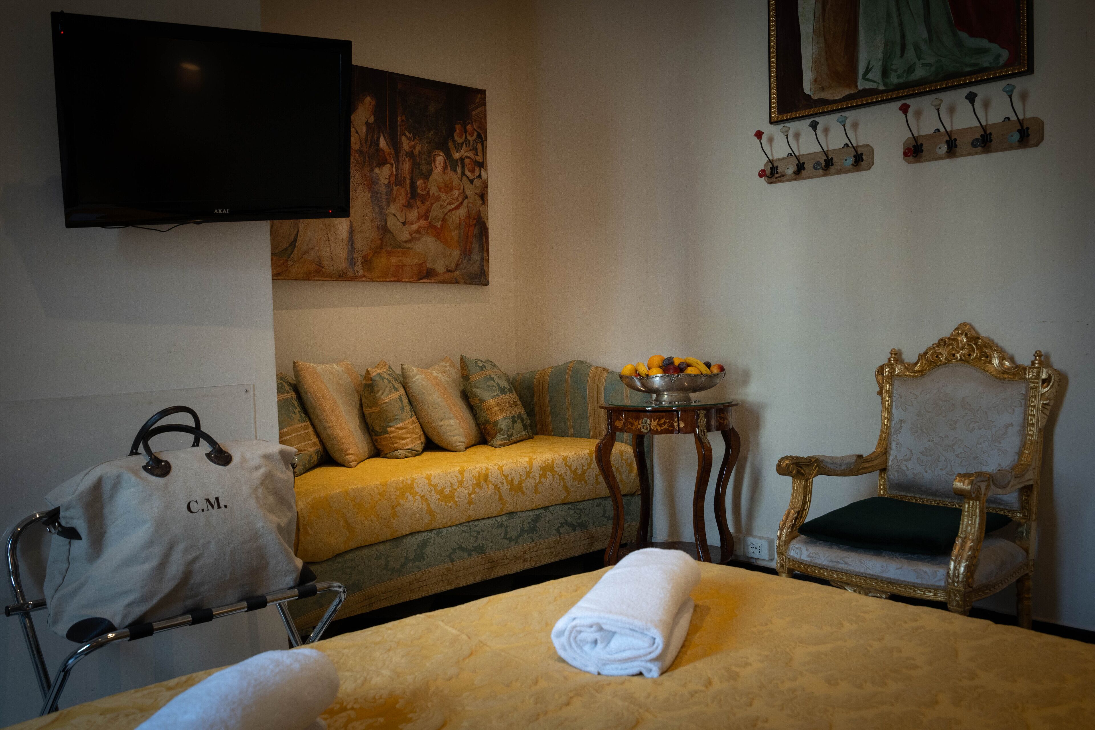 A hotel room with a bed, a sofa, a chair, a television, and a painting on the wall.