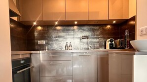 A modern kitchen with stainless steel appliances, wooden flooring, and a backsplash. - Le Marais, rue de Bretagne Square du Temple - Elie Wiesel (Paris)