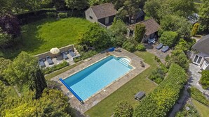 An aerial view of a residential property with a swimming pool, a patio area with lounge chairs, and a garden. - Tastefully furnished spacious cottage - perfect for family gatherings! (Buckland Newton)