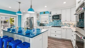 A modern kitchen with a central island, white cabinetry, and blue accents. - 7BR Pet-Friendly Home w/ EV Charger & Room for 18+ Guests (Bethany Beach)