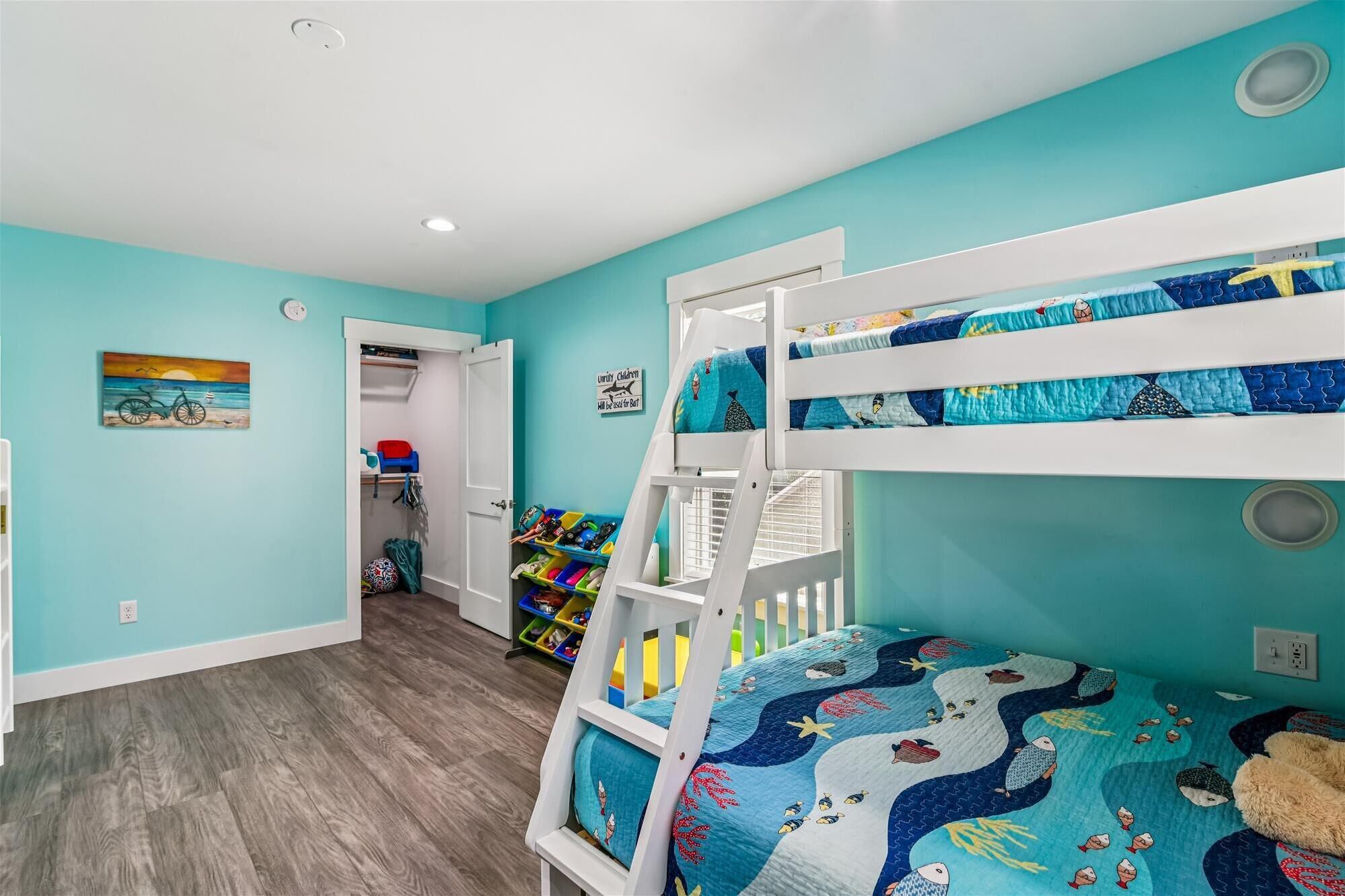 A child's bedroom with bunk beds, a closet, and a painting on the wall.