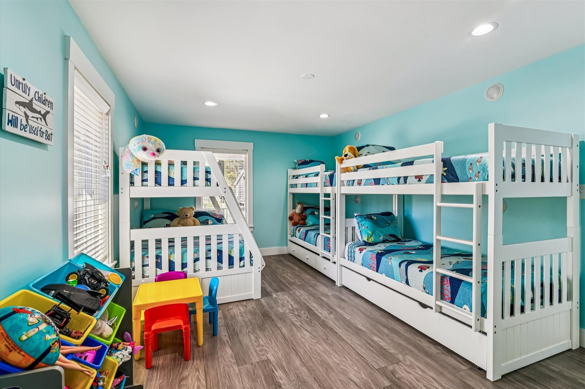 Ein Kinderzimmer mit Etagenbetten, einem Spieltisch und Aufbewahrungsboxen.