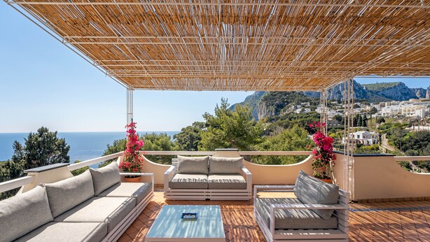 A terrace with a wooden pergola, a sofa set, a coffee table, and potted plants. - Oliveto Capri (Capri)
