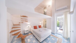 A bedroom with a large bed, a staircase, a balcony, and a view of the outdoors. - Oliveto Capri (Capri)