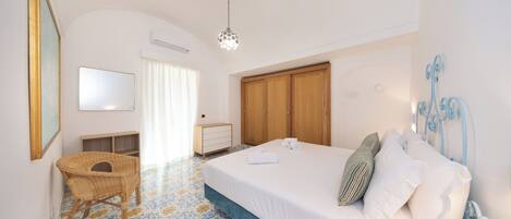 A bedroom with a bed, a chair, a wardrobe, and a mirror.