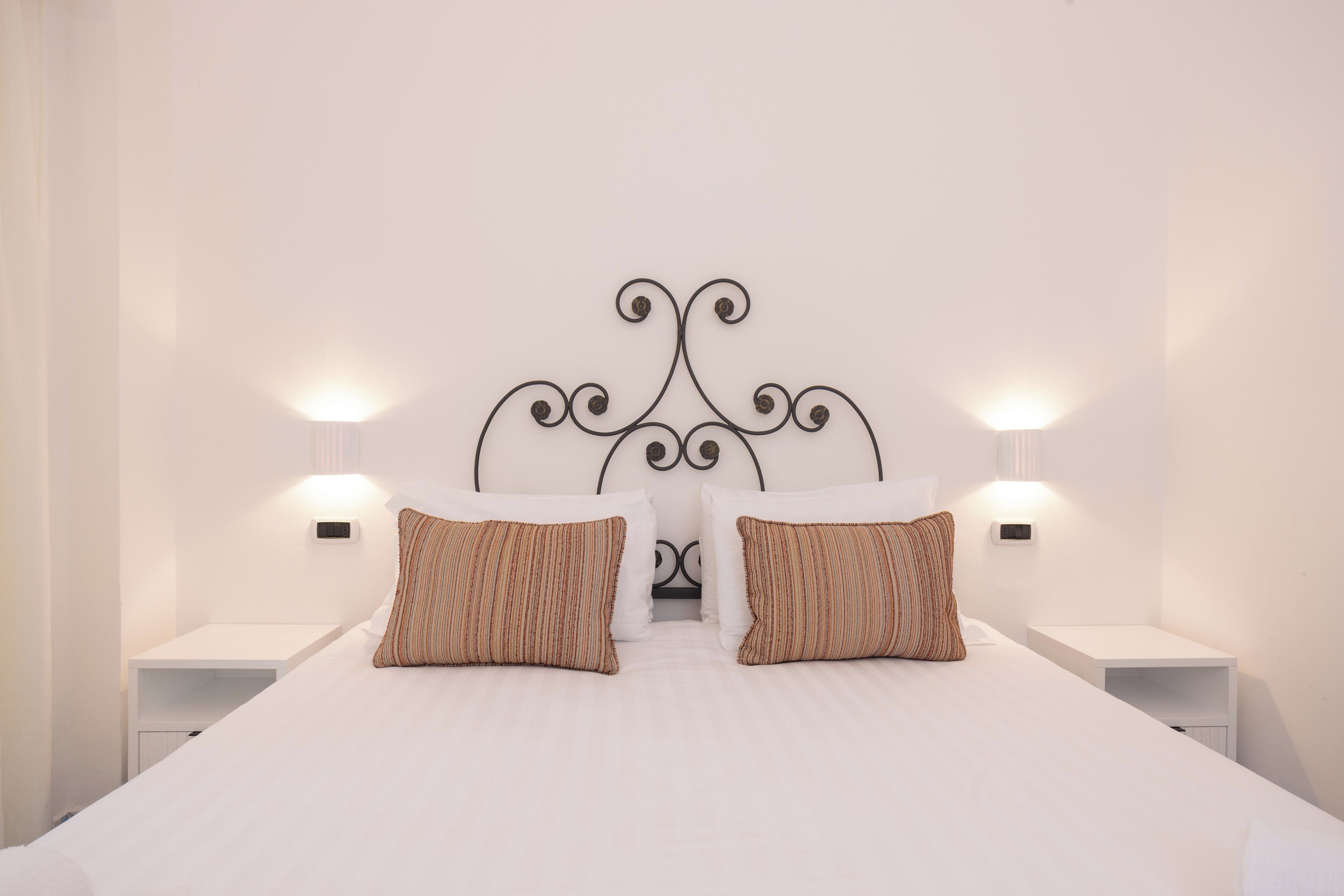 A neatly made bed with two pillows, a white headboard, and two bedside lamps.