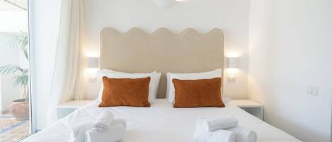 A hotel room with a large bed, two brown pillows, white bedding, and two bedside lamps.