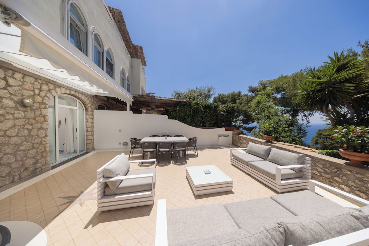 A patio with outdoor furniture, a dining table, and a stone wall.