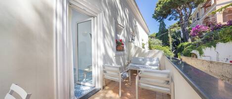 Ein Balkon mit weißer Möbel, einer Tür und einem Topfpflanze.