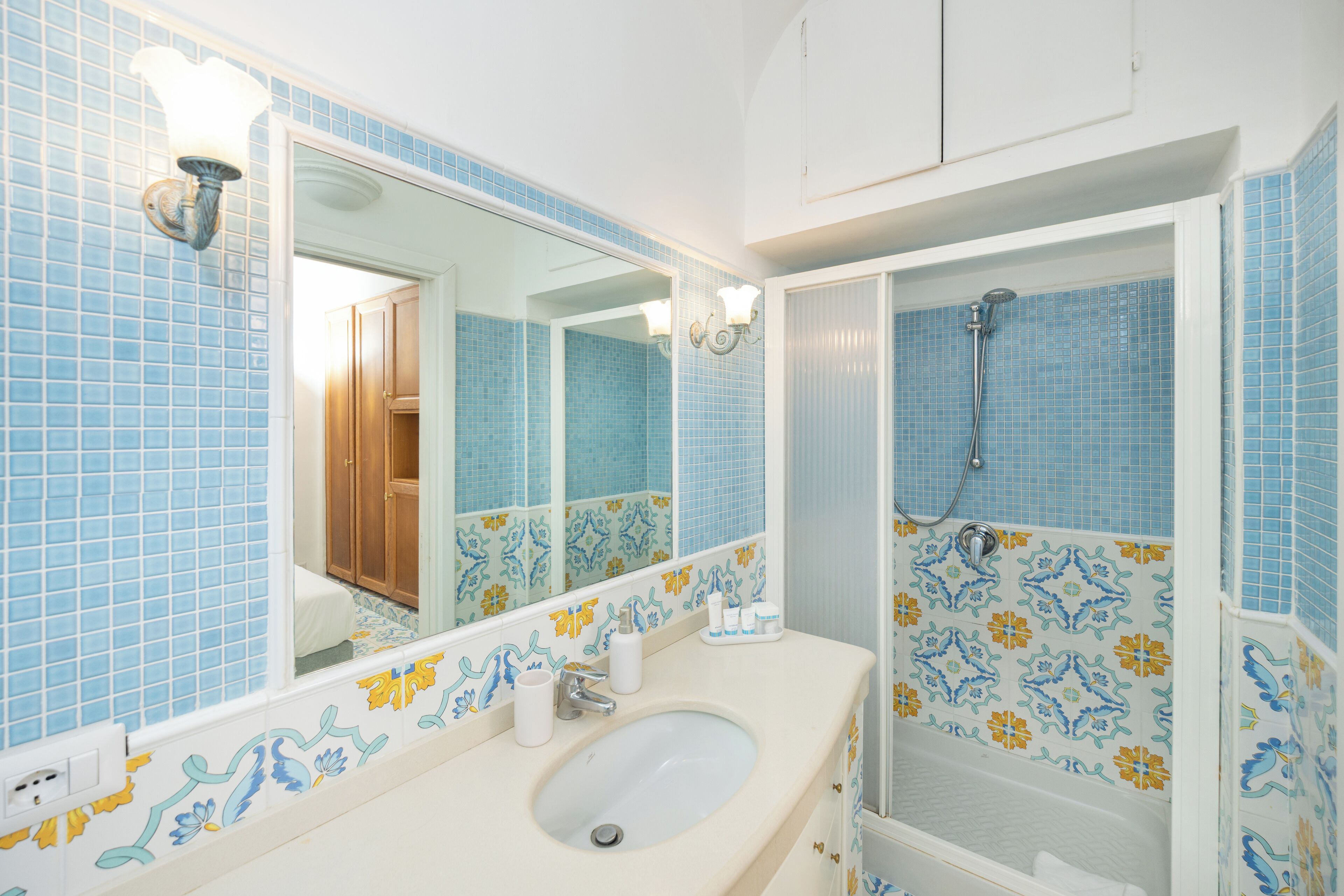 A bathroom with a sink, mirror, and shower.