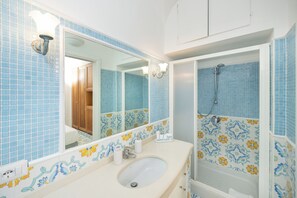 A bathroom with a sink, mirror, and shower.