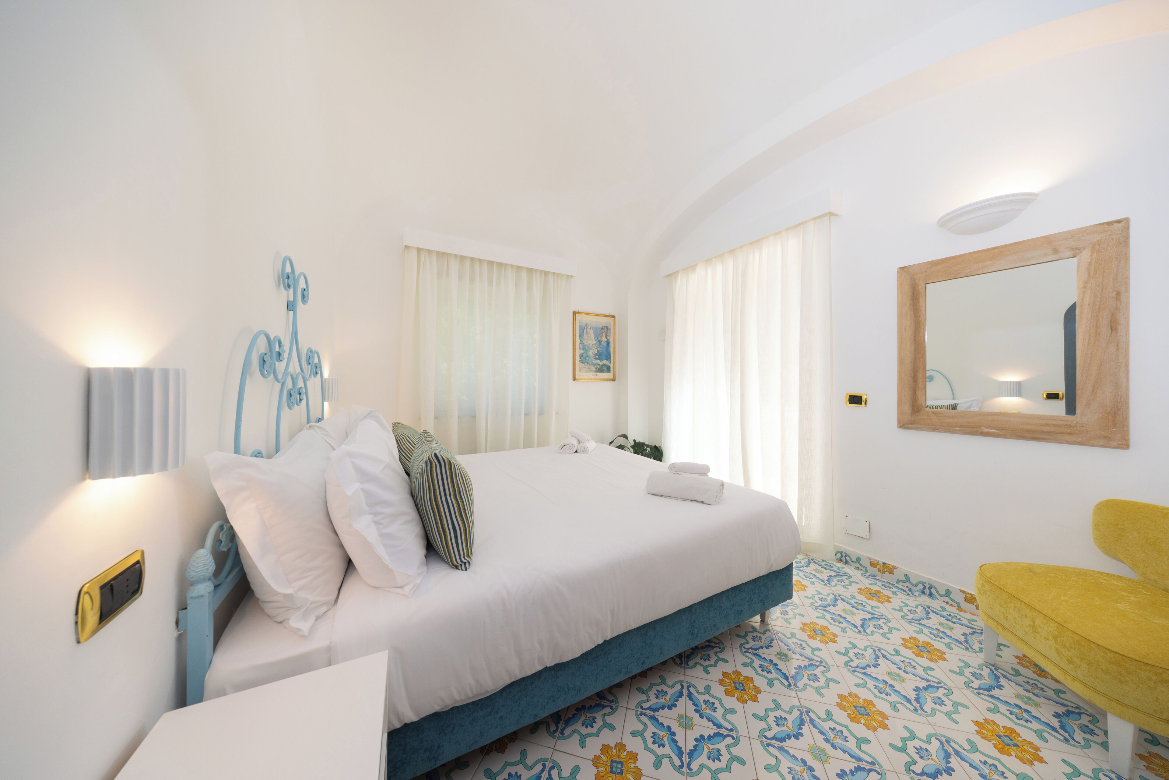 A hotel room with a bed, bedside table, and a yellow armchair.