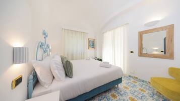 A hotel room with a bed, bedside table, and a yellow armchair.