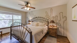 Un dormitorio con cama, mesitas de noche, ventilador de techo y ventana.