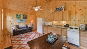 A wooden cabin interior with a kitchen, dining area, and living room.