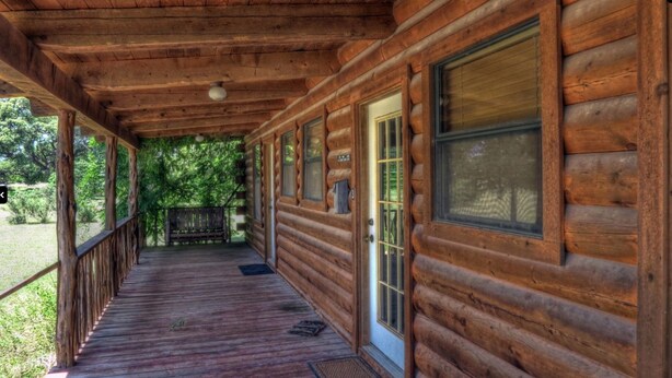 A wooden cabin with a covered porch, large windows, and a door with a glass panel.