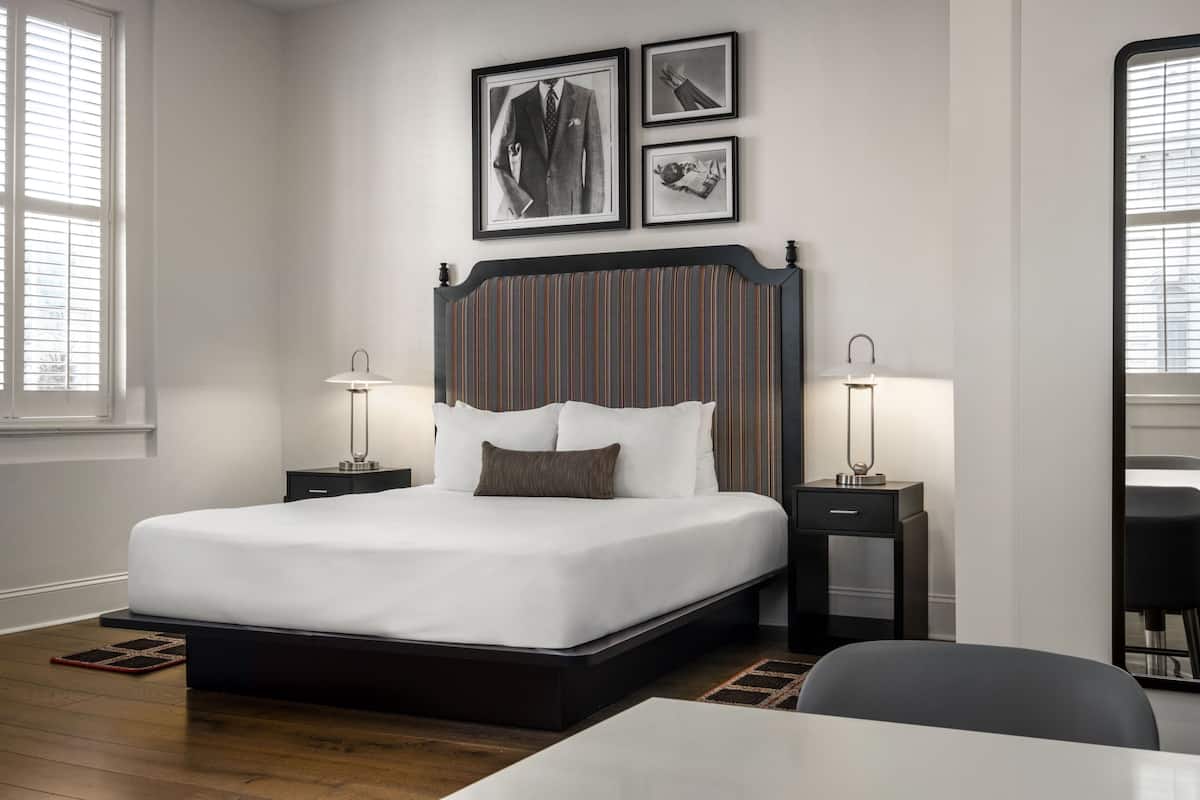 Ein ordentlich eingerichtetes Schlafzimmer mit einem großen Bett, Nachttischen, einem Schreibtisch und einem Stuhl.