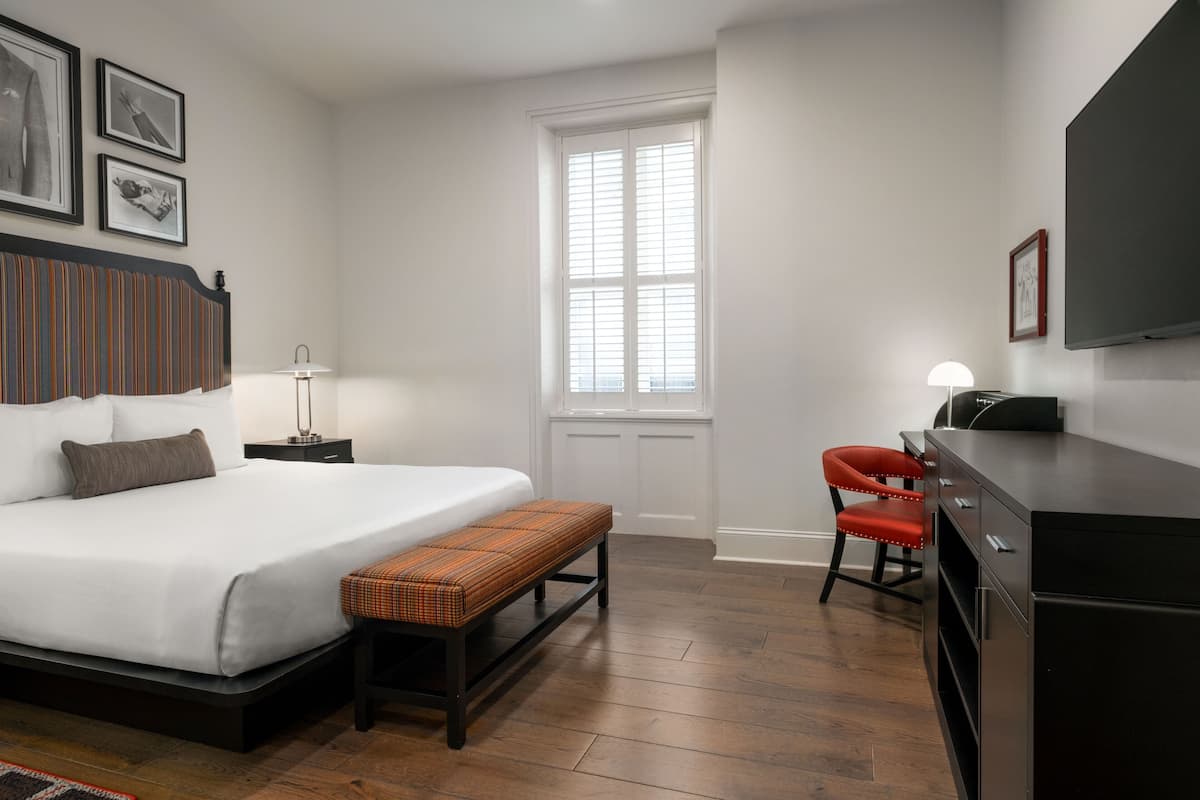 Ein Schlafzimmer mit einem großen Bett, einer Bank, einem Schreibtisch und einem Stuhl.