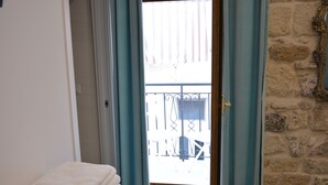 A room with a view of a balcony, a stack of white towels, and a stone wall. - AFFITTACAMERE DIMORA DEL CARMINE (Bari)