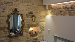 A stone wall with two ornate mirrors and a small shelf with flowers. - AFFITTACAMERE DIMORA DEL CARMINE (Bari)