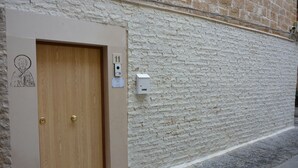 A wooden door with a number plate, a wall-mounted electrical box, and a small sign with a drawing. - AFFITTACAMERE DIMORA DEL CARMINE (Bari)