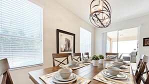 A dining room with a wooden table set for four, white plates, and silverware.