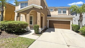 A two-story house with a garage, a small porch, and a well-maintained lawn.