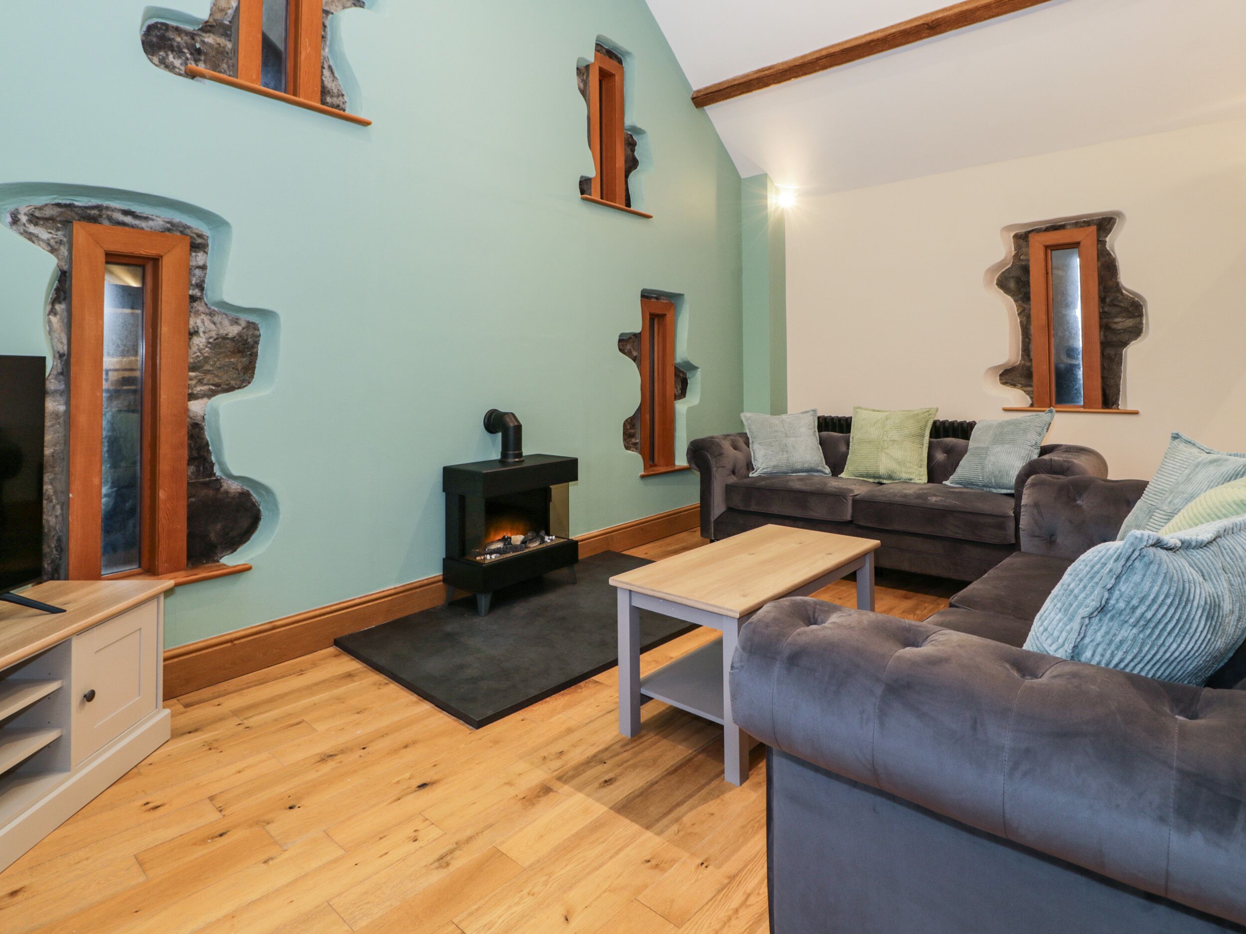 Una sala de estar acogedora con chimenea, un conjunto de sofás y un televisor.