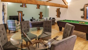 A cozy living room with a pool table, comfortable seating, and a fireplace. - The Barn by Lyons (Talybont)