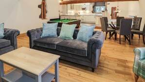 A cozy living room with a sofa, a coffee table, and a pool table. - The Barn by Lyons (Talybont)