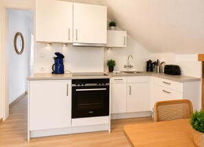 A modern kitchen with white cabinets, a black oven, a coffee maker, and a toaster.