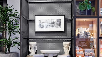 Una estantería moderna de tonos oscuros con un cuadro enmarcado, objetos decorativos y una planta en maceta.