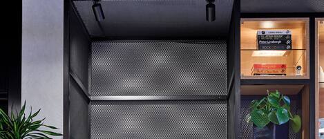 Una estantería moderna de tonos oscuros con un cuadro enmarcado, objetos decorativos y una planta en maceta.