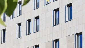 Un edificio de hotel con fachada moderna, múltiples ventanas y un logotipo visible.