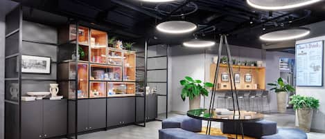 A modern interior with a central seating area, a bookshelf, and a menu board.