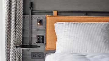 Une chambre à coucher moderne avec une tête de lit en bois, une table de chevet avec une lampe et une prise électrique.