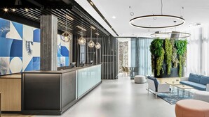 Un intérieur moderne comprenant un comptoir d’accueil, un espace détente et un mur végétal agrémenté de plantes.
