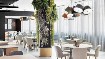 En modern inredning med runda bord, stolar och en central pelare som är dekorerad med grönska.