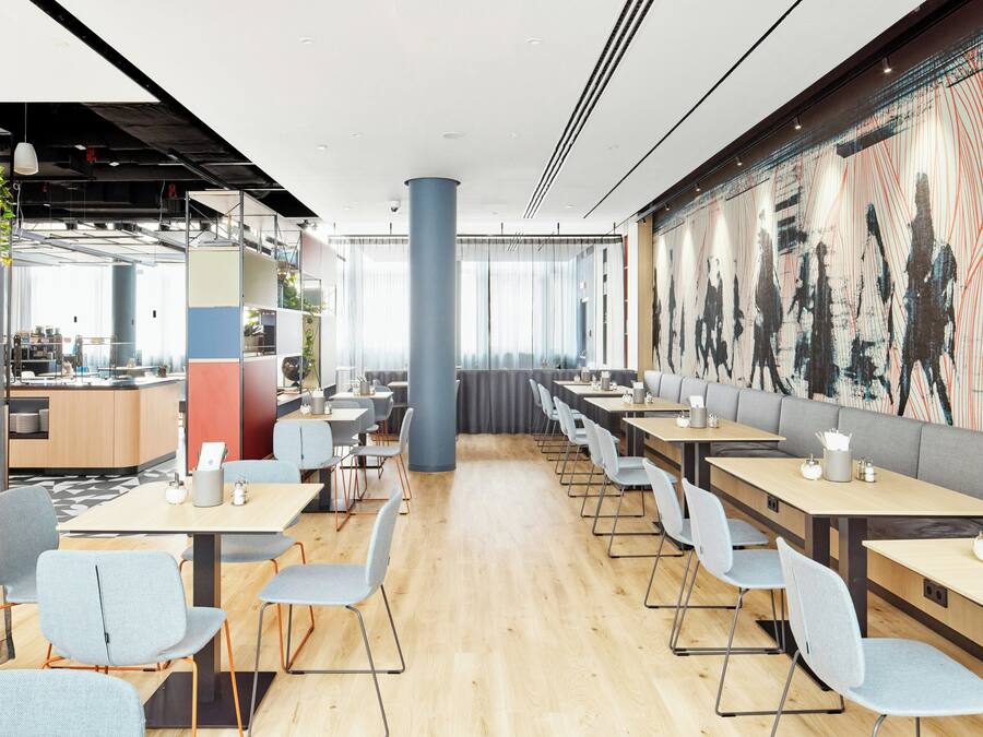 A modern restaurant with a long counter, multiple tables, and chairs.