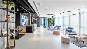 A modern interior with a reception desk, seating area, and large windows.