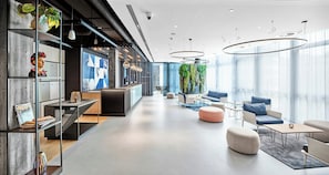 A modern interior with a reception desk, seating area, and large windows. - Hotel Wien-Schönbrunn (Vienna)